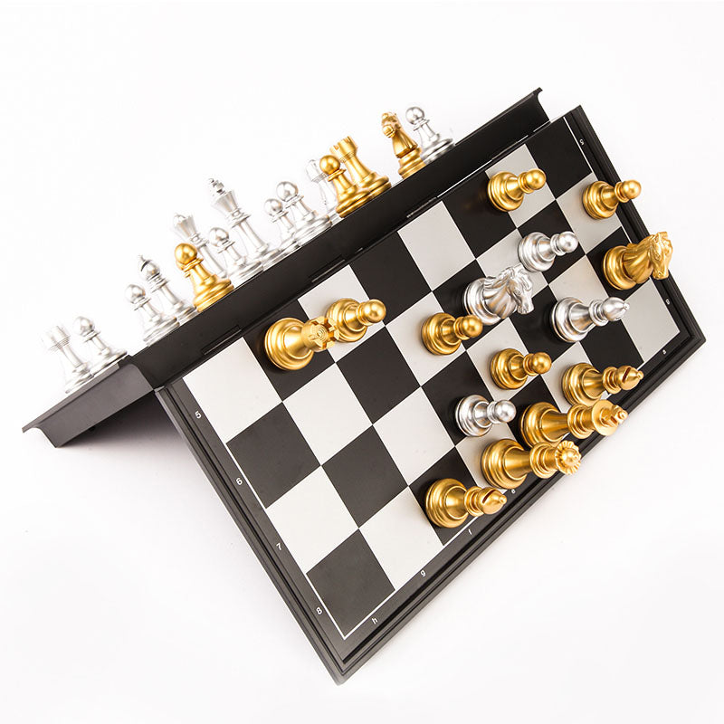 A folding magnetic chess board being closed mid-game with metallic pieces clinging to the angled surfaces.