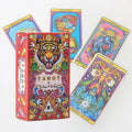 A small red tiger-themed tarot box resting on its side next to scattered, colorful psychedelic card backings.