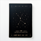 Front view of a matte black hardcover Cancer zodiac journal featuring a gold star map constellation design centered on a clean white background.