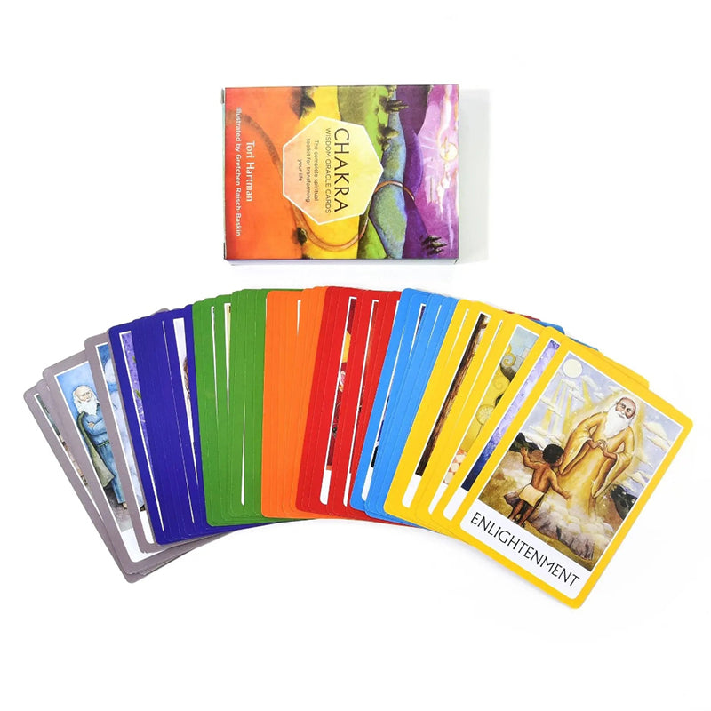 A full 49-card deck of the Chakra Wisdom Oracle fanned open horizontally below its protective outer box casing. The cards display highly distinct color-coded chakra suit borders, with a prominent yellow-bordered card on the right titled Enlightenment showing a spiritual guru figure.