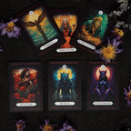 Six gothic tarot cards arranged in two rows on a black sand surface decorated with dried purple flowers. The cards displayed include Temperance, Queen of Coins, The Wheel of Fortune, Ace of Cups, The Moon featuring a blue werewolf, and a dark horned High Priestess card.