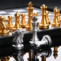 Low-angle close-up of metallic silver and gold chess pieces reflecting on a glossy black surface.