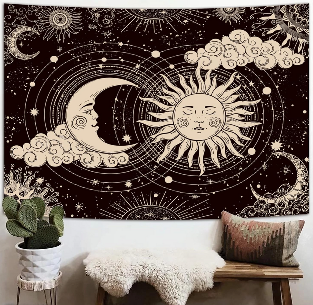 Aesthetic black and white celestial tapestry featuring a mystic sun and a crescent moon with faces, surrounded by stars, clouds, hanging behind a small bench and plant. 