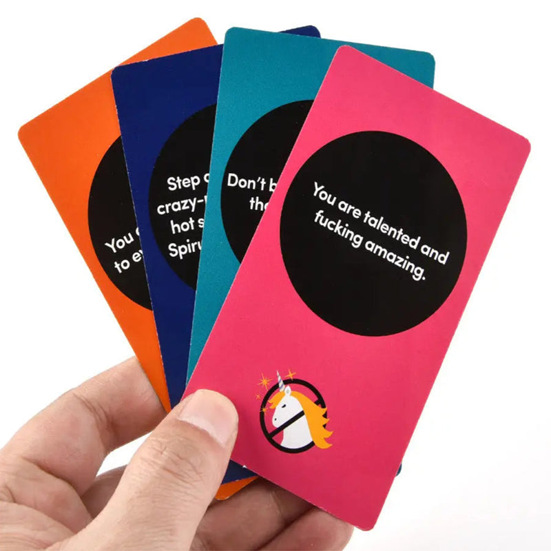 Rebel Deck oracle cards fanned out in hand showing vibrant orange blue teal pink cardstock layout. The hot pink card displays direct motivational advice reading You are talented and fucking amazing inside a black circle graphic with the signature rebellious unicorn logo at the base.
