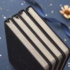 Top view close-up of three black hardcover journals stacked together, showcasing their thick cream-colored inner paper edges and sturdy sewn book spines.
