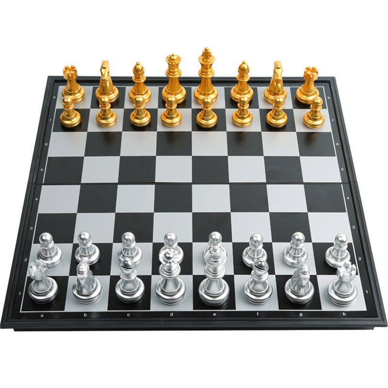 Full top-down perspective view of a black and white magnetic chess board with silver and gold armies aligned.