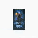 Front view of the Witches Tarot card box against a white background, featuring the author's name Ellen Dugan at the top and the title in stylized blue text at the bottom. The central artwork depicts a blonde witch holding a glowing torch in a dark, blue-lit forest.