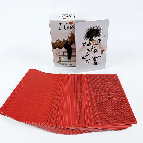 A large stack of red divination cards with geometric patterns fanned out in front of the white I Ching product box.