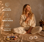 A lifestyle product image of a woman meditating with the Anima Premium Crystals 7 Chakra set in a warm, serene setting. Graphic text callouts highlight the wellness benefits: Create Balance, Tune to Inner Peace, and Awaken Vitality, alongside the raw stones and an open guide booklet.