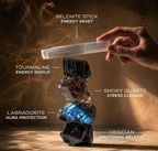 A product infographic from Anima Crystals detailing the properties and meanings of the protection stones stacked vertically against a warm backdrop. The infographic links the Selenite Stick to Energy Reset, Black Tourmaline to Energy Shield, Smoky Quartz to Stress Cleanse, Labradorite to Aura Protection, and Black Obsidian to Emotional Release.