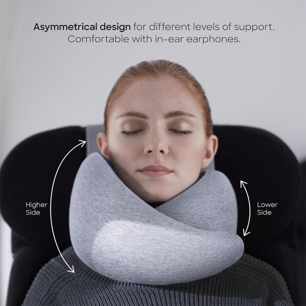 Ergonomic travel neck pillow in the corporate goth travel collection, shown supporting neck and chin with an asymmetrical heather gray modal-blend cover, contoured memory foam, and adjustable hook-and-loop closure.