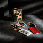 The Pulp Tarot lifestyle flatlay presents the full 78-card divination deck arranged beneath dramatic studio shadow lighting on a textured surface. The promotional product spread features the book-style magnetic box standing upright alongside individual illustrated cards like The Magician, The High Priestess, and The King of Pentacles, positioned next to the instruction guidebook and patterned card back.