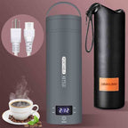 A product layout of the QRAGJBM space grey portable electric travel kettle showing its digital LED temperature display set to 212 degrees Fahrenheit next to a black leather storage bag. The image features the detachable white power plug accessories on the top left and a steaming cup of fresh coffee at the bottom left.