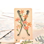 Two of Rods tarot card featuring vintage medical drawings of crossed leg bones wrapped in orange flowers.