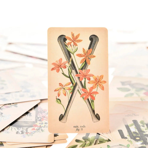 Two of Rods tarot card featuring vintage medical drawings of crossed leg bones wrapped in orange flowers.